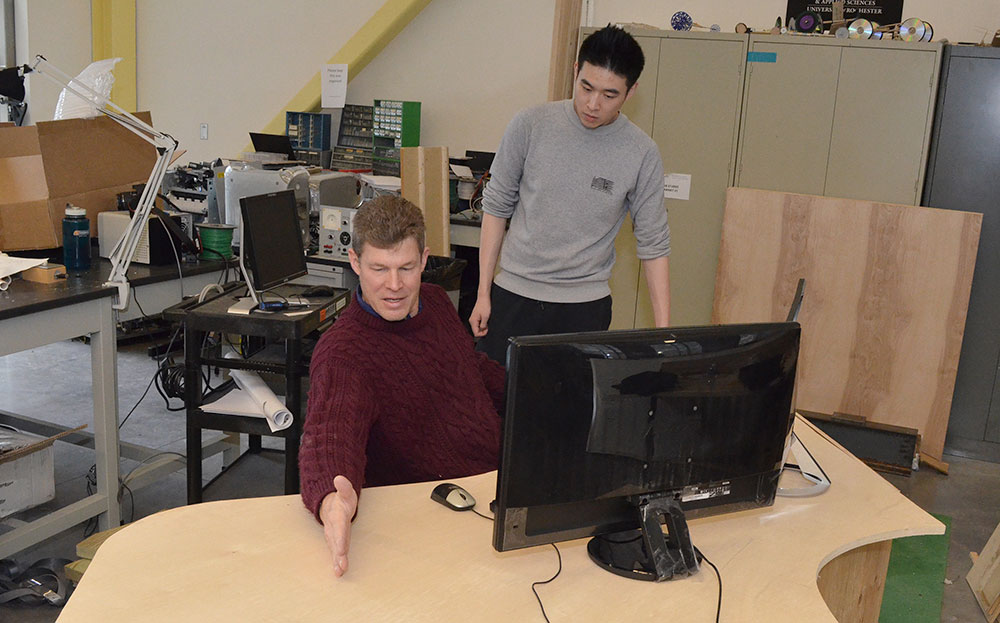 student and professor examine a prototype desk