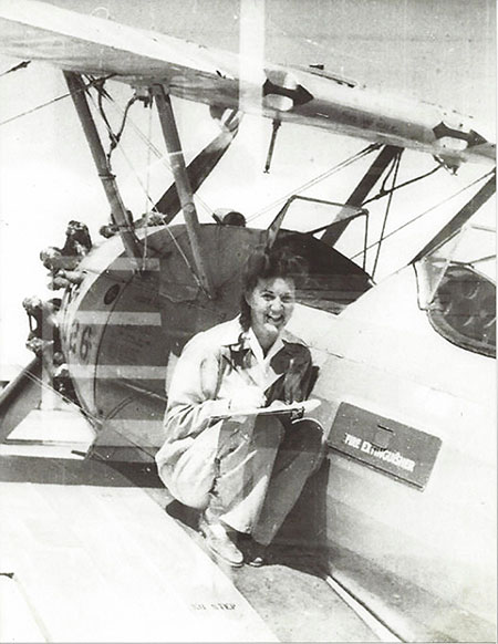 World War II photo of women posing next to a plane