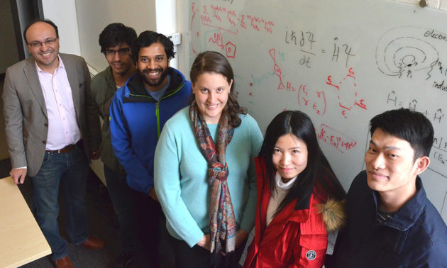 professor poses with students in front of white board