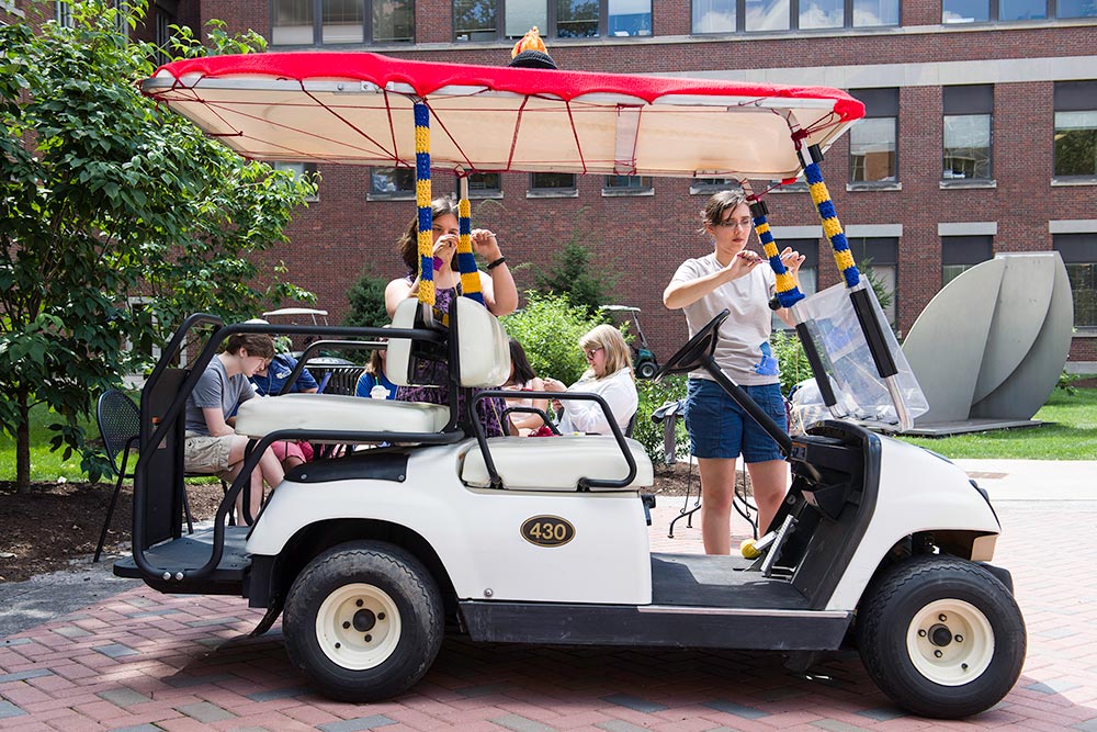 students knitting blue and yellow stripes onto a golf cart