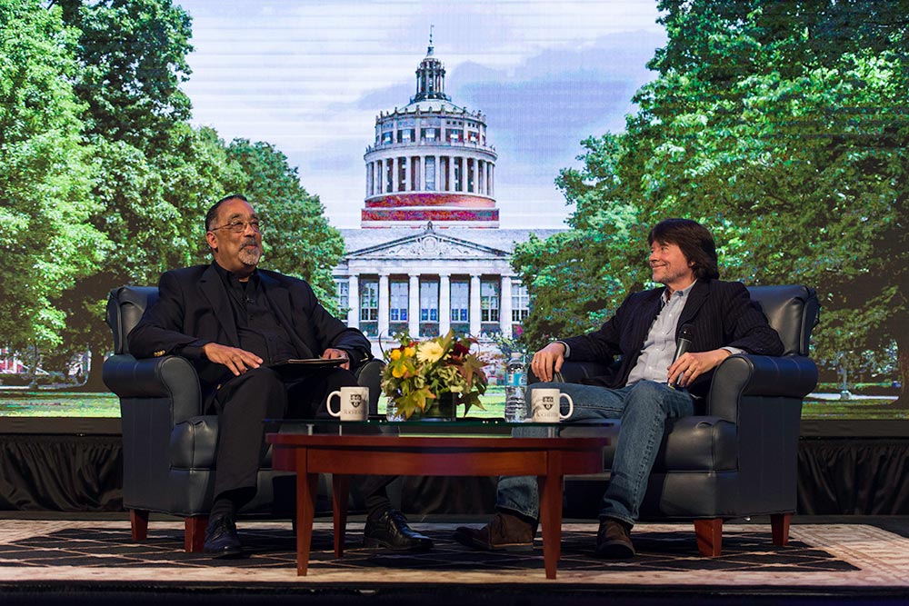 Paul Burgett and Ken Burns seated on stage