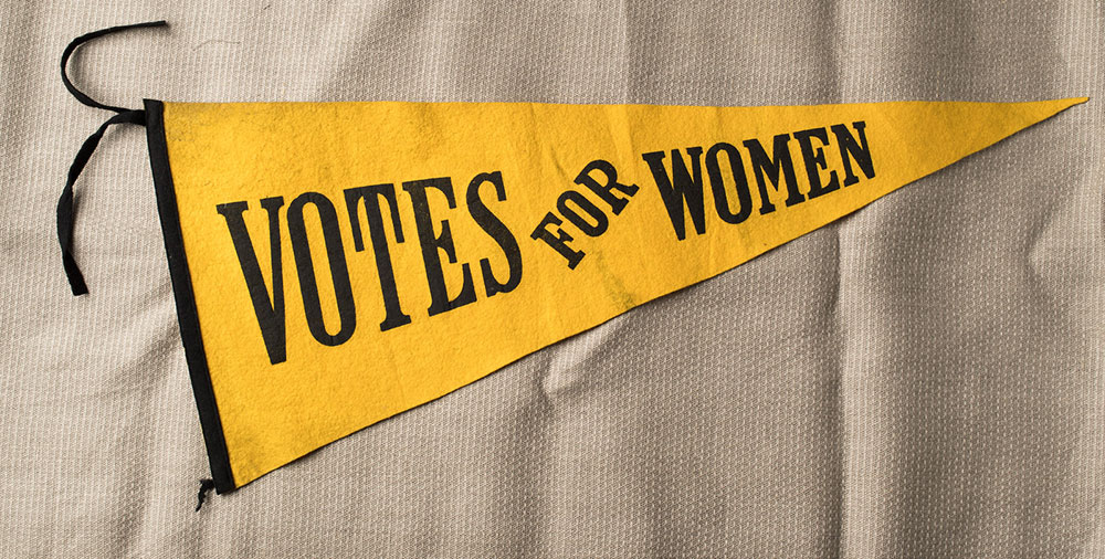 yellow penant reads VOTES FOR WOMEN
