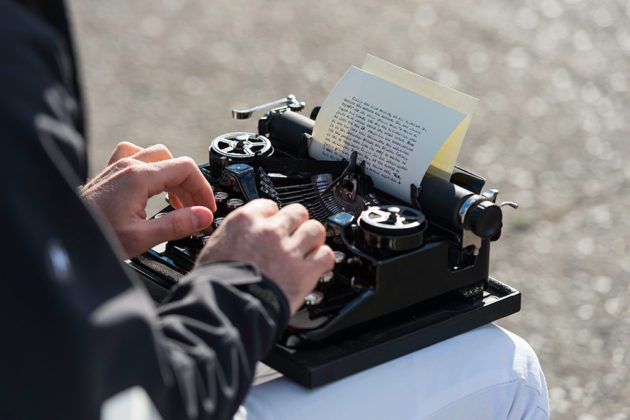 close-up of hands typing on old typewriter