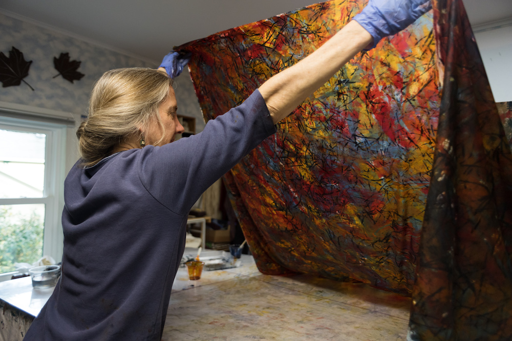 artist holds up dyed fabric