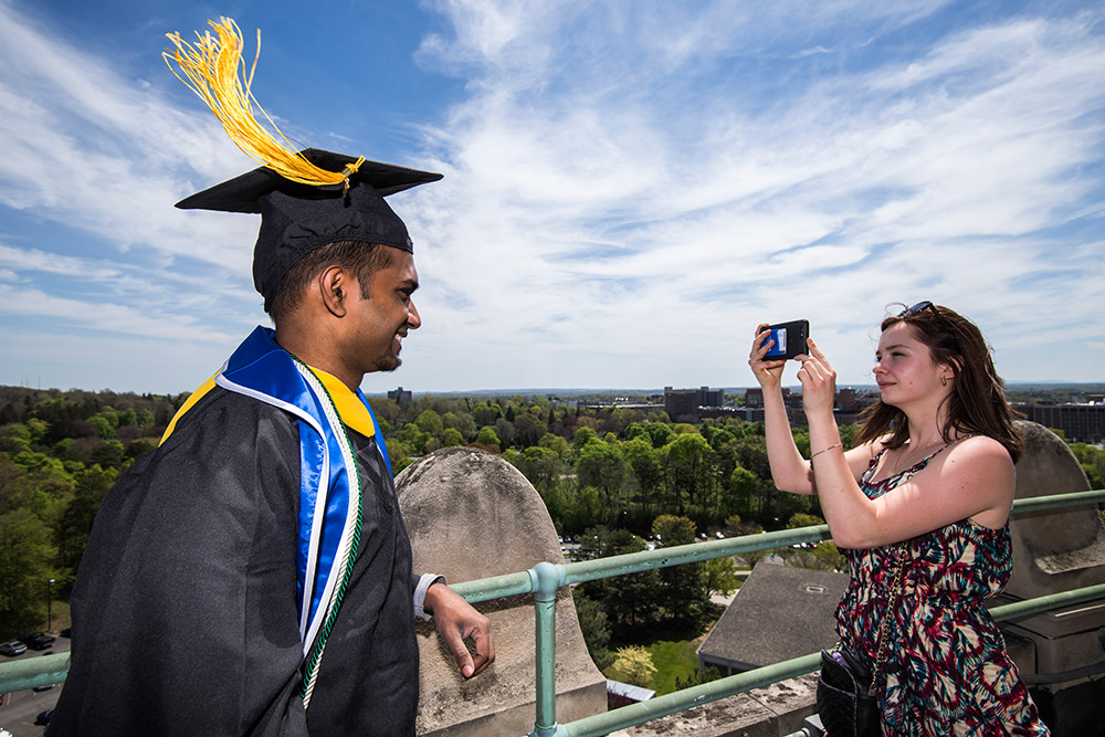 graduate in cap and gown gets picture taken on top of library tower