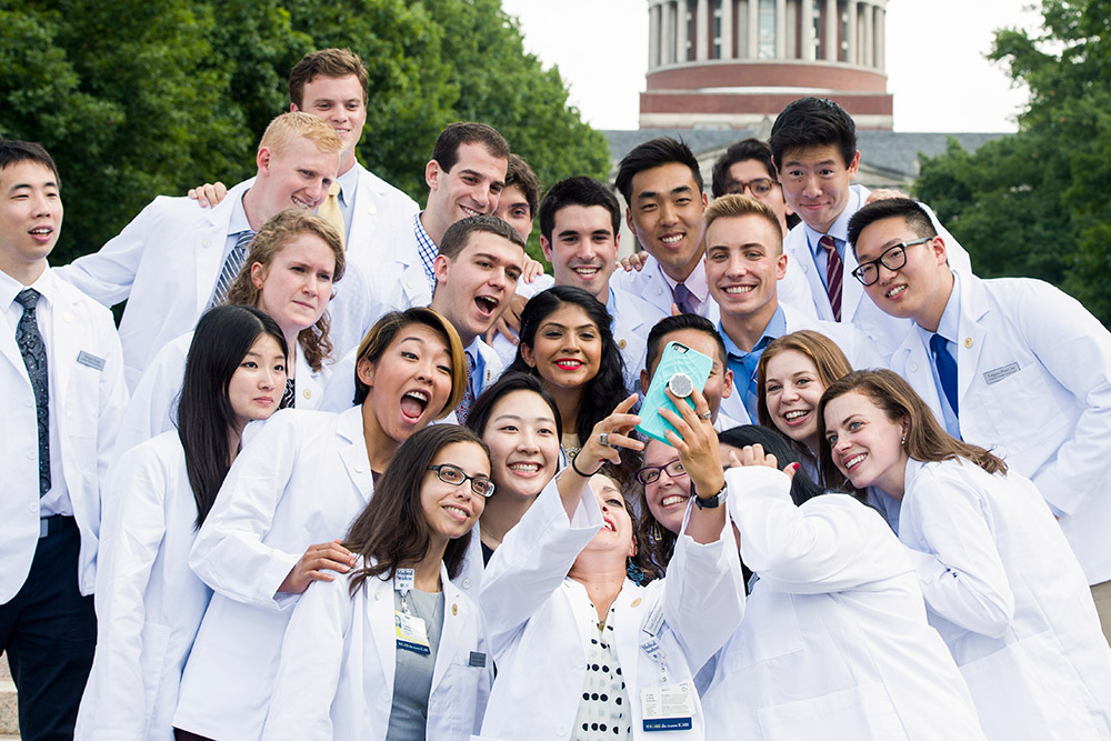 large group of medical students in white coats taking selfies