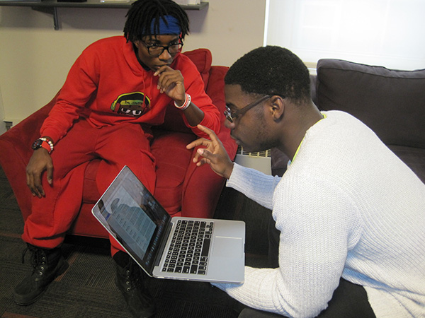 two students talking over a laptop