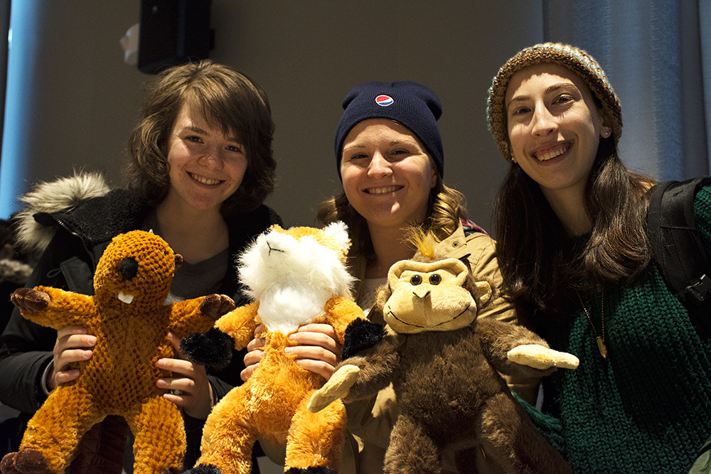 three students holding stuffed animals