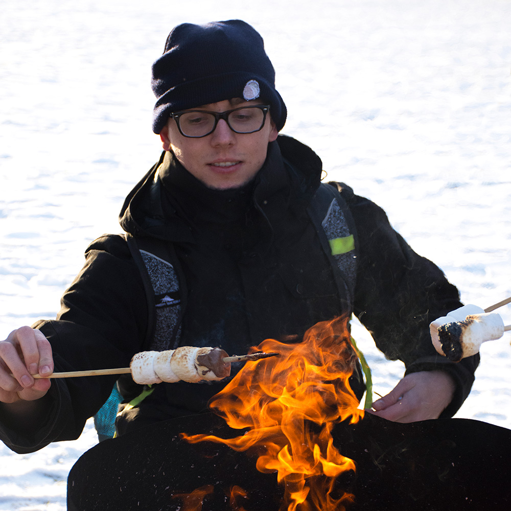 student toasting marshmallows over a fire