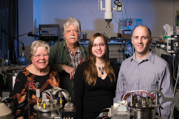 group of four scientists pose for a photo in their lab