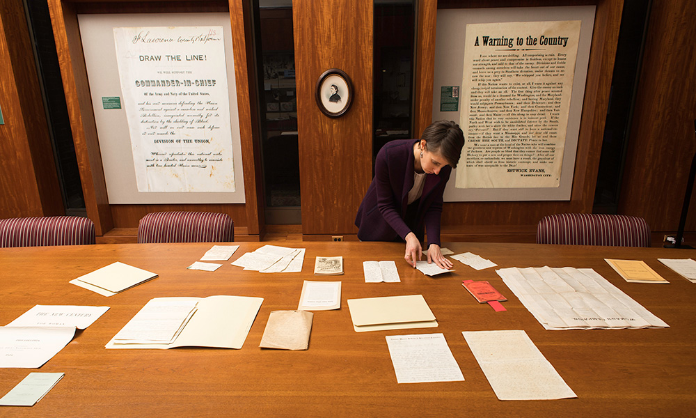 librarian looks through examples of collections on a long table.