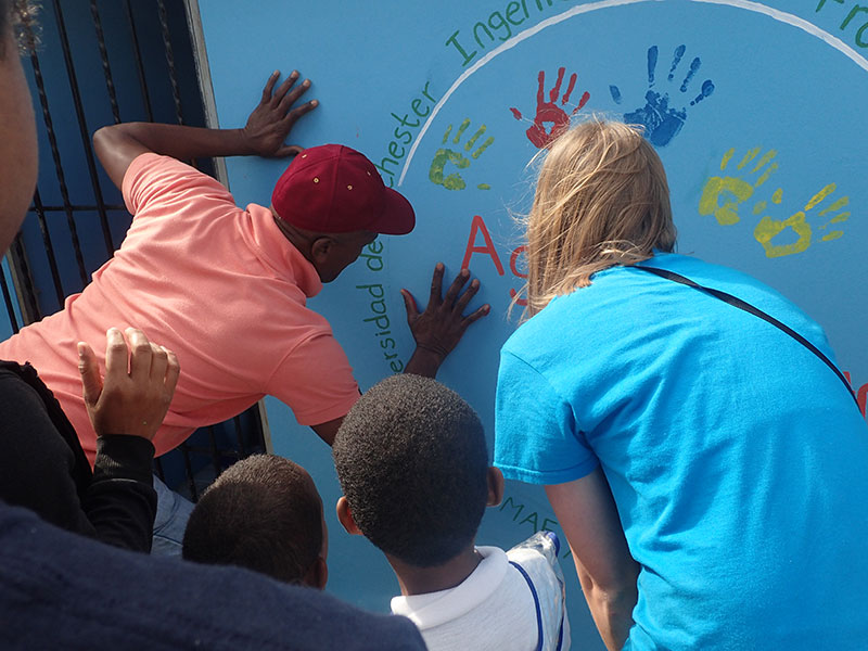 people making painted handprints on a wall