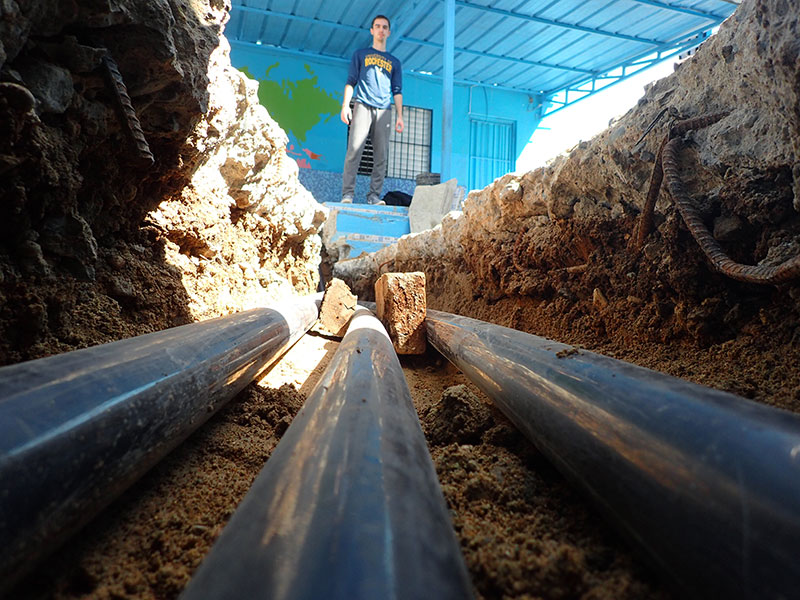 student examines pipes in the ground