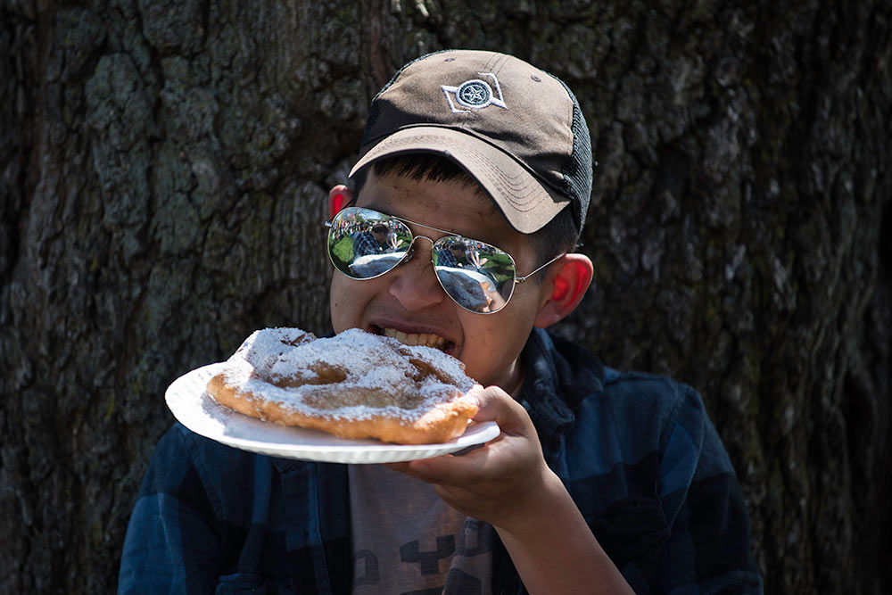 guy in sunglasses eating fried dough