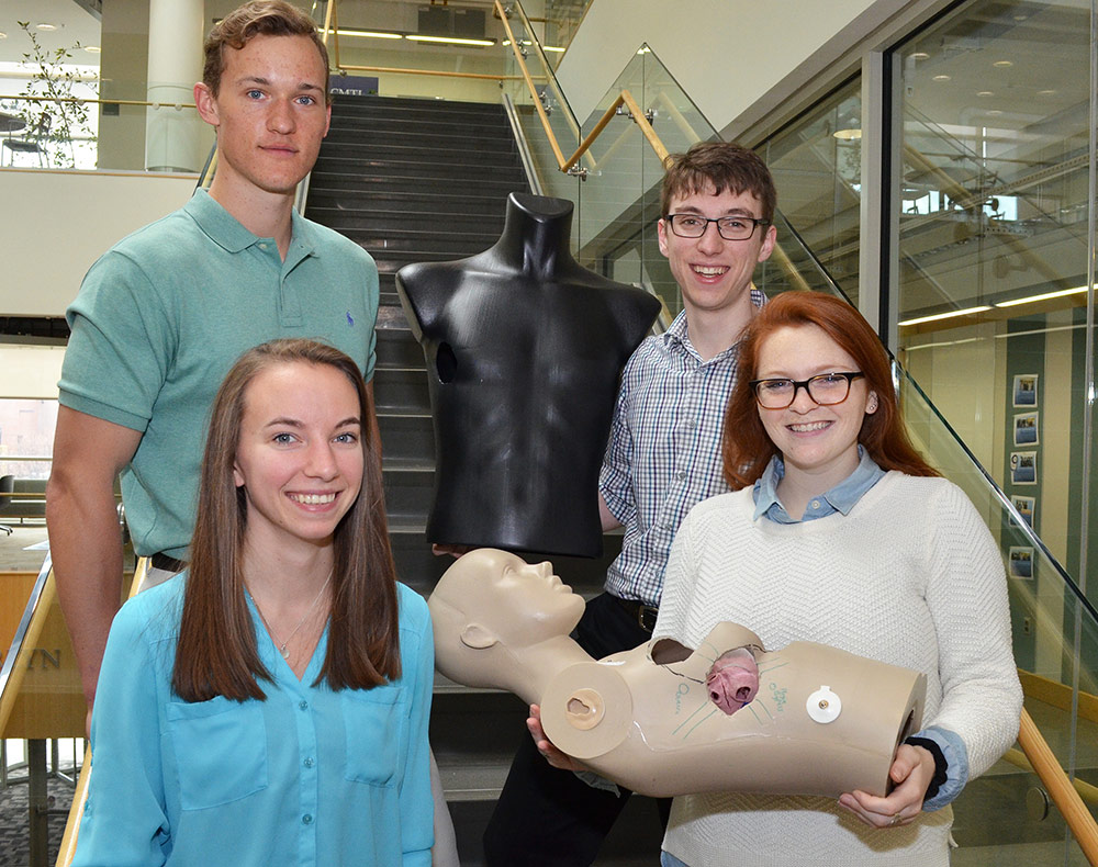 four students, one holding a model of a torso