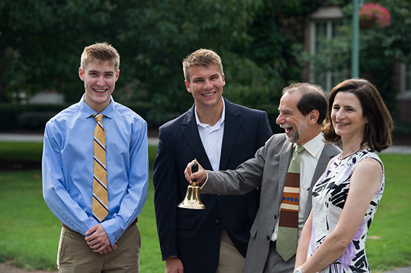 Rich Feldman with two students and Maryann Mavrinac, ringing a bell outside Rush Rhees Library