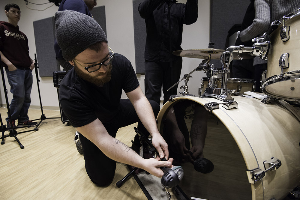 student places mic on drum
