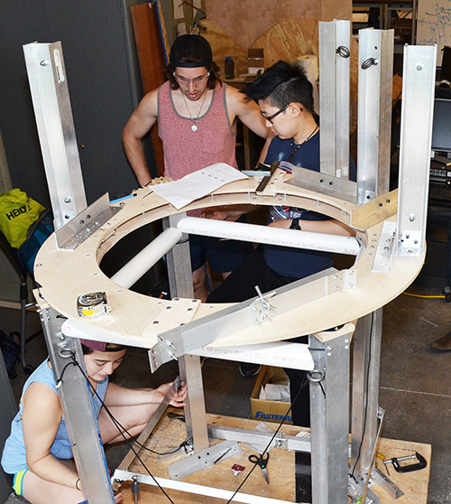 students assemble metal struts on a wood platform