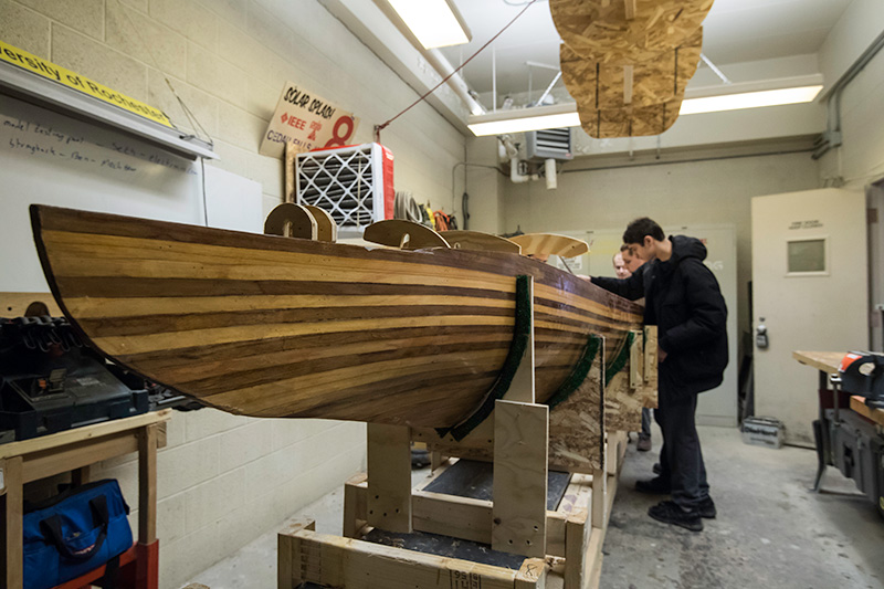 students working on wooden boat