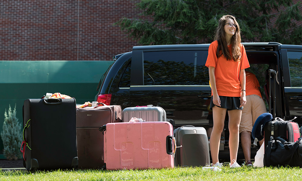 student standing next to car filled with luggage