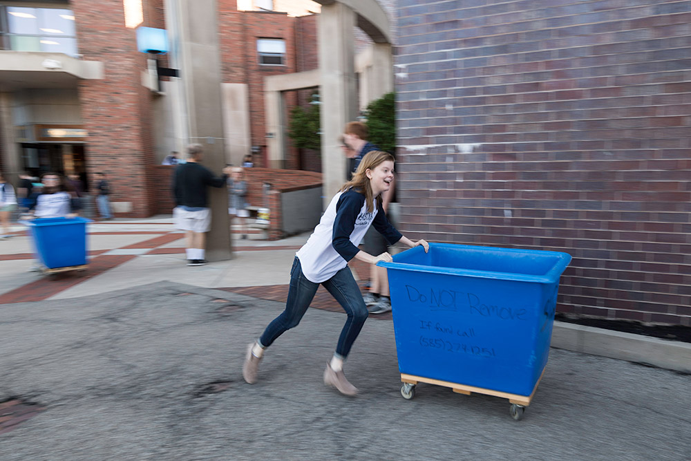 student running, pushing a large blue cart
