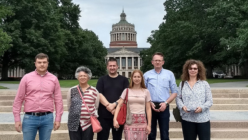 group photo of six people standing in front of library