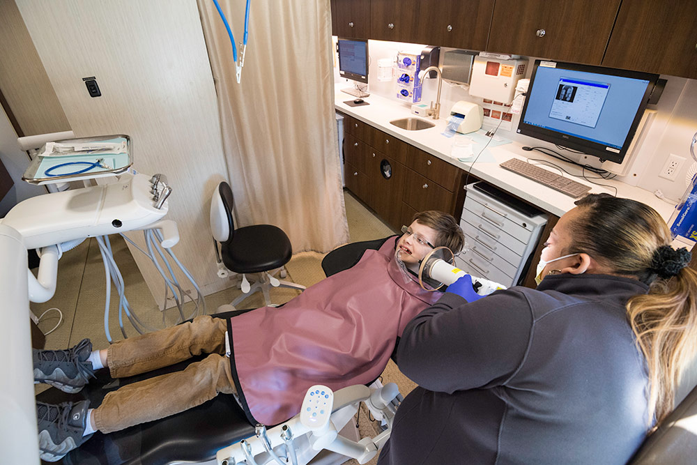 overhead view of dental technician examining boy in a dentist chair