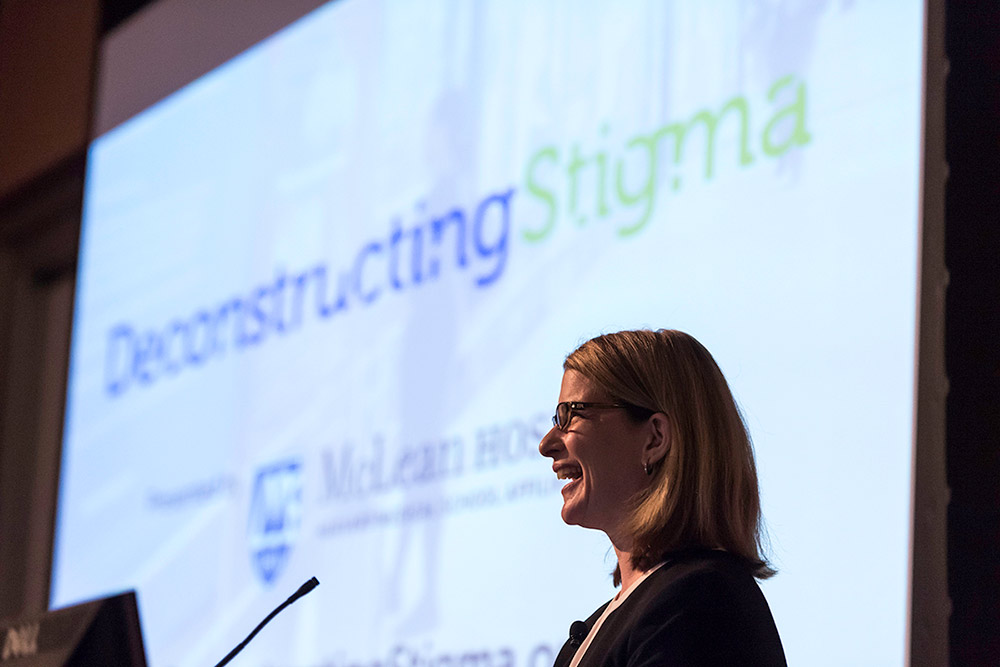 smiling woman in front of presentation slide reading DeconstructingStigma