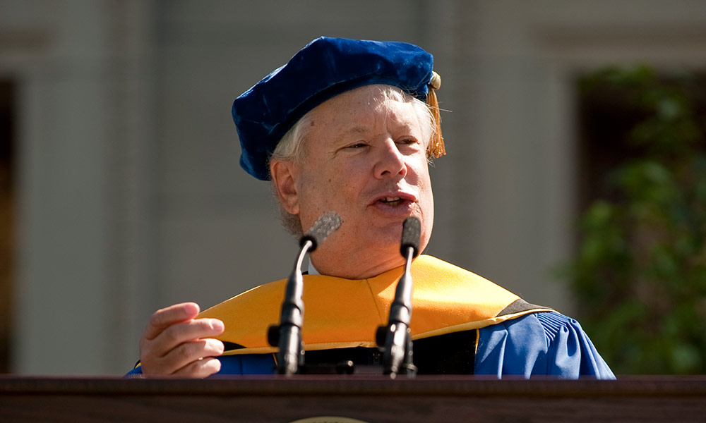 person in academic regalia giving a speech at a Rochester commencement ceremony