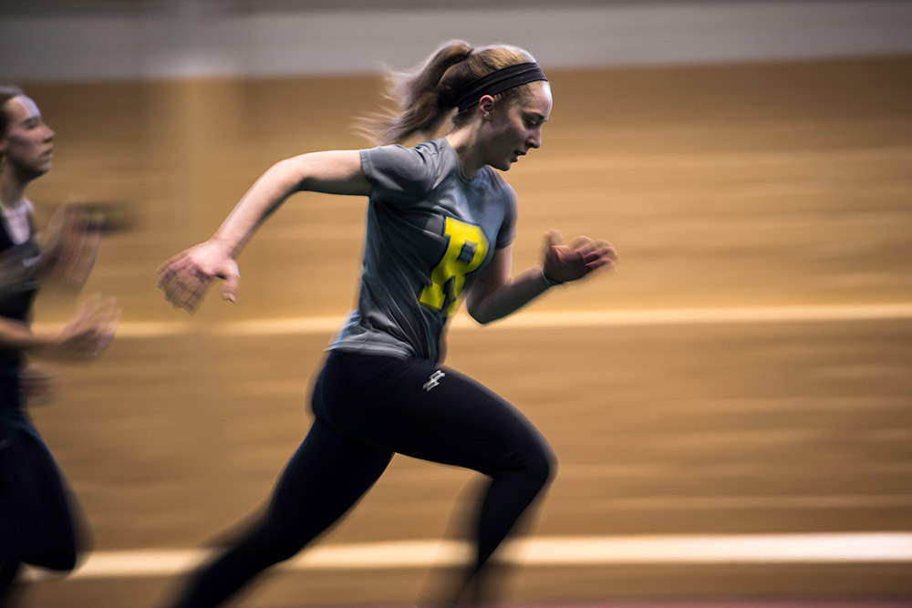 student athlete running on an indoor track