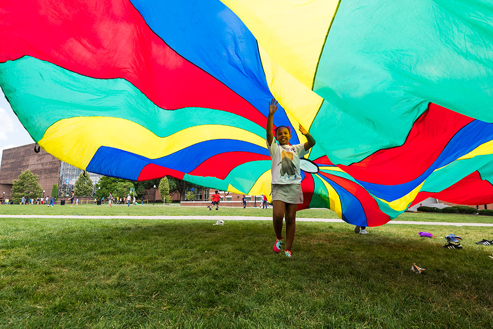 child playing under a colorful parachute