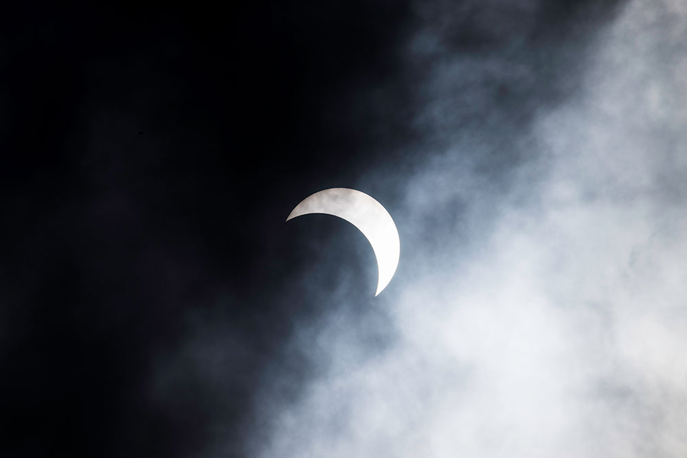 partial solar eclipse behind clouds