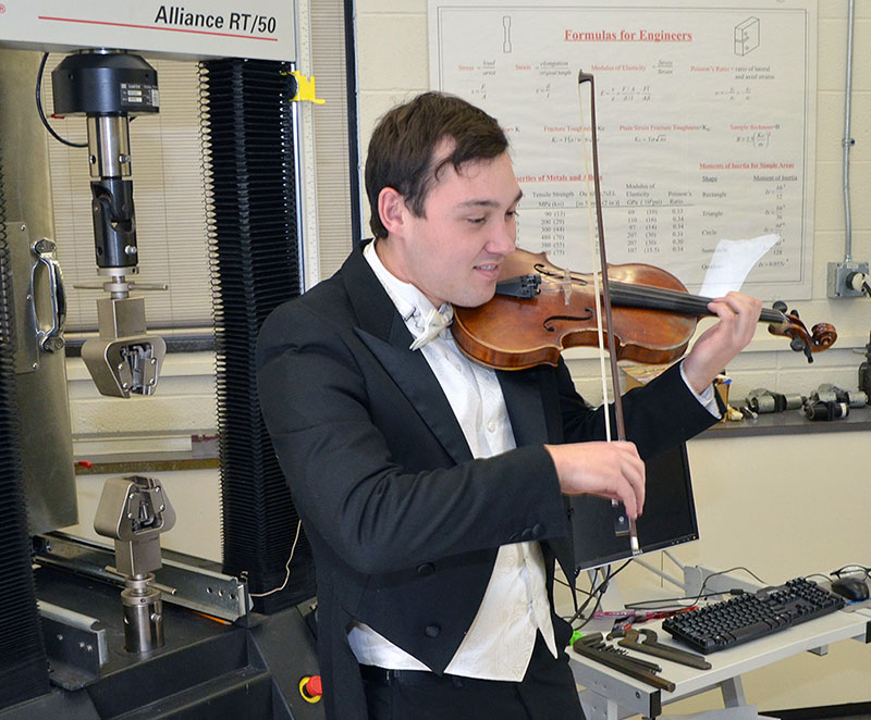 student playing the violin in an engineering lab