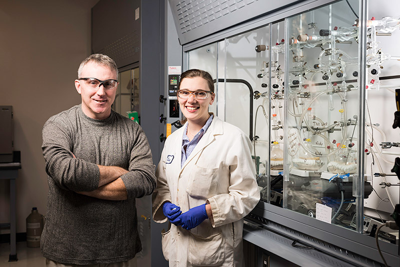 two researchers, smiling, in lab