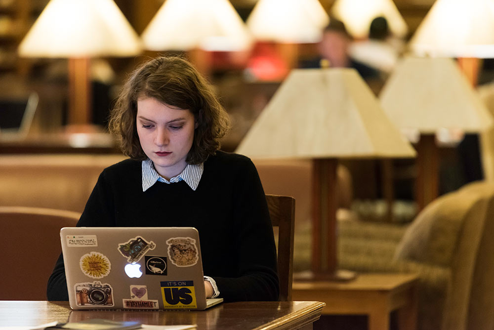 young woman with her sticker covered laptop in a library
