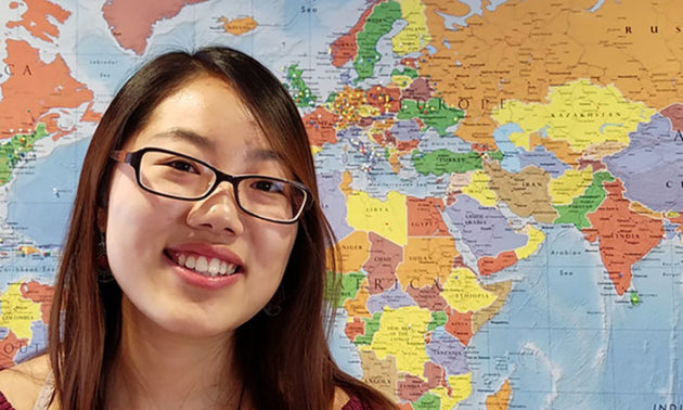 still from a video featuring a young woman smiling in front of a map