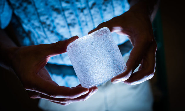 researcher holding a large cube of ice with bubble trapped in it