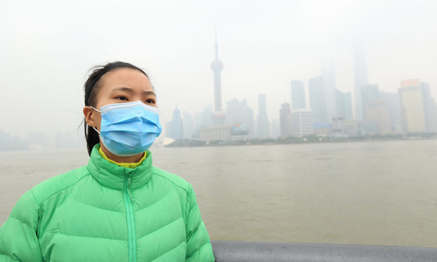 woman in a mask with polluted skyline of Beijing in the background