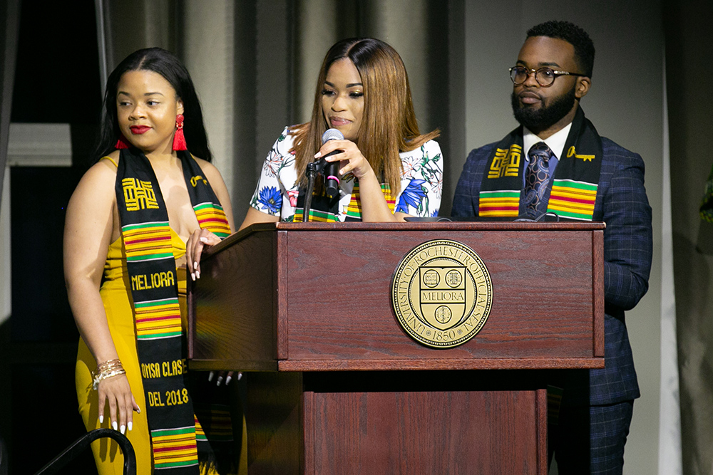 three students behind the podium