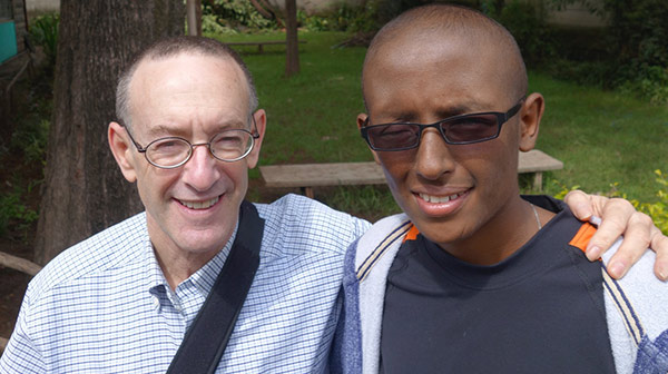doctor with his arm around his patient, a young man in sunglasses, both smiling
