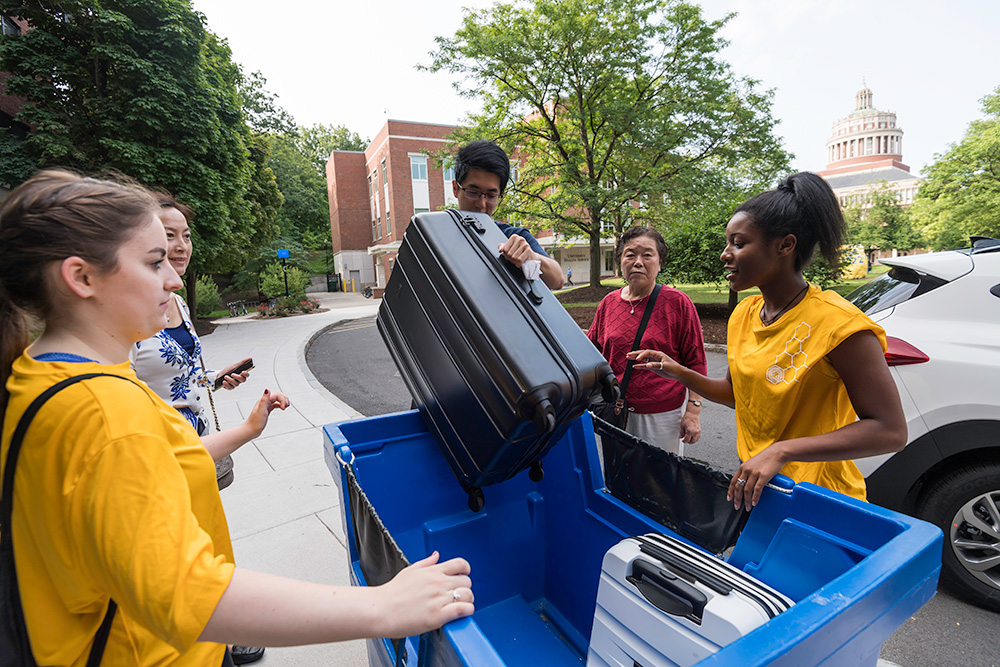 group of students removing luggage from a large blue tote