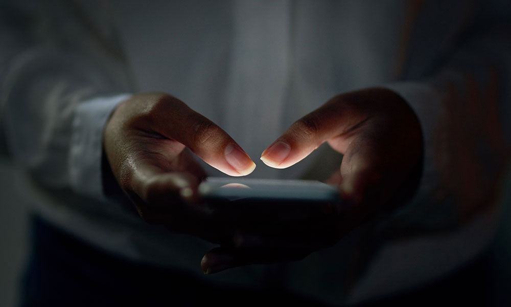 close-up of hands typing on a cellphone