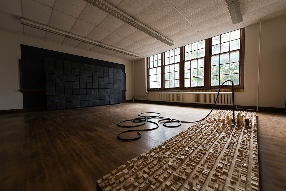 a large room with a wooden floor, and on the floor are wooden blocks the appear to form a cityscape or skyline