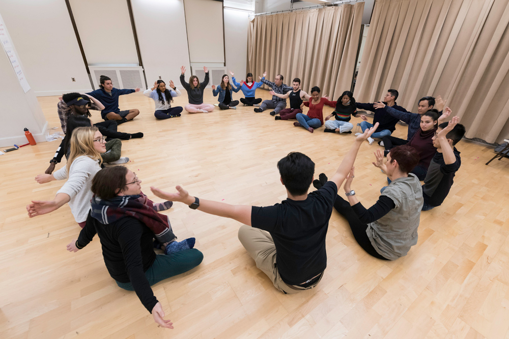 circle of students sitting on the floor of a dance studio