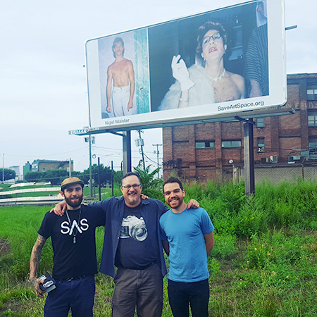 three people posing in front of a billboard showing SaveOurSpace logo