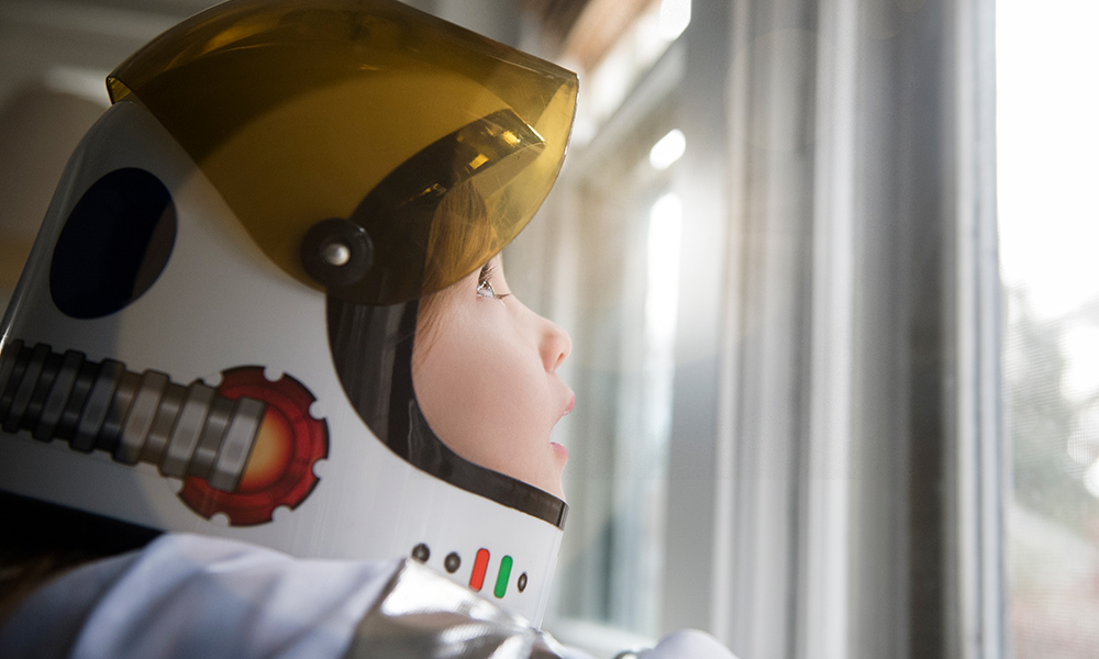 child in space helmet looks up at the sky in wonder