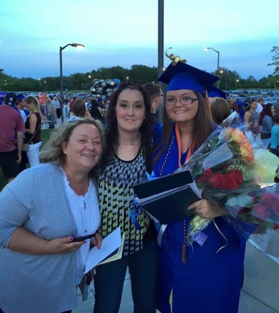 graduate stands with family members