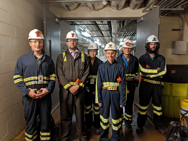 Dark matter experts with hard hats in a group photo.