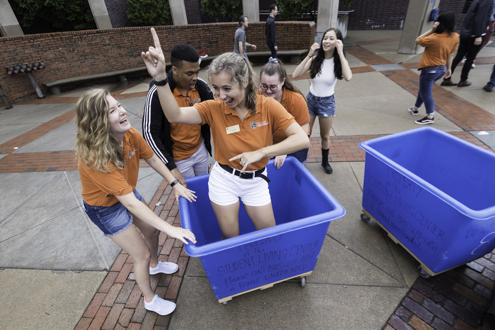 students dancing in blue wheelie bins.