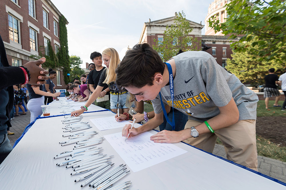 student line up at a table to sign the class roll